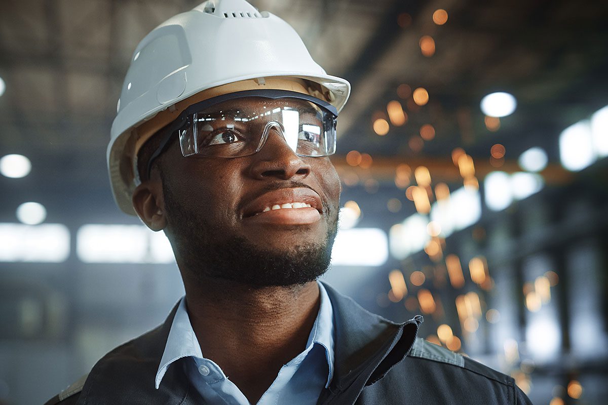 Happy Professional Heavy Industry Engineer Worker Wearing Uniform, Glasses and Hard Hat in a Steel Factory